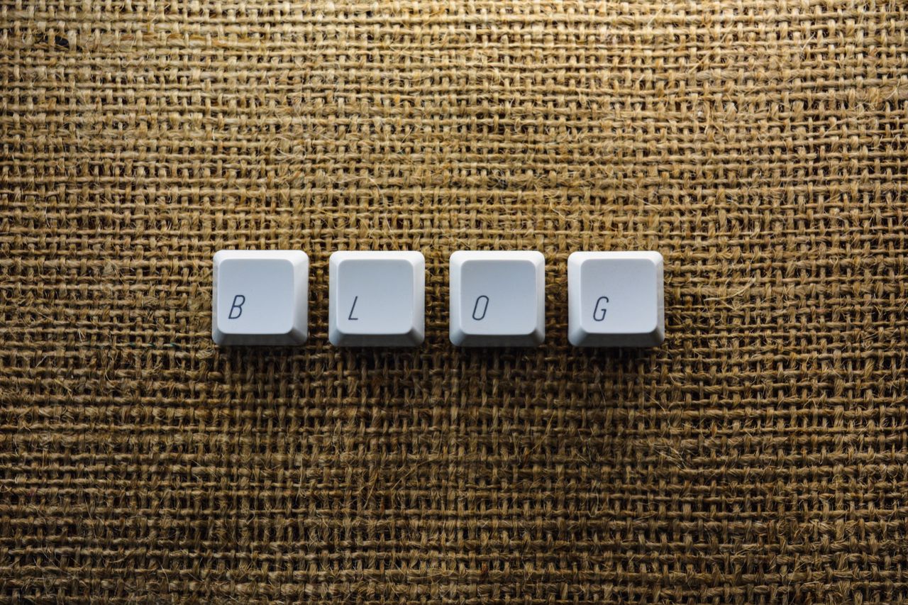 The Art of Drawing Readers In: Your attractive post title goes here Close-up of keyboard keys spelling 'BLOG' on a burlap surface, ideal for tech blogs.