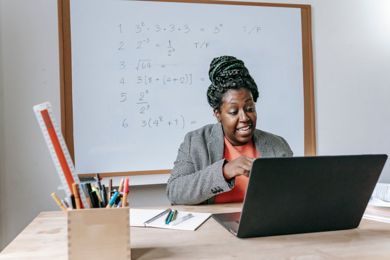 About Amazed African American female giving lecture in mathematics online on netbook in classroom